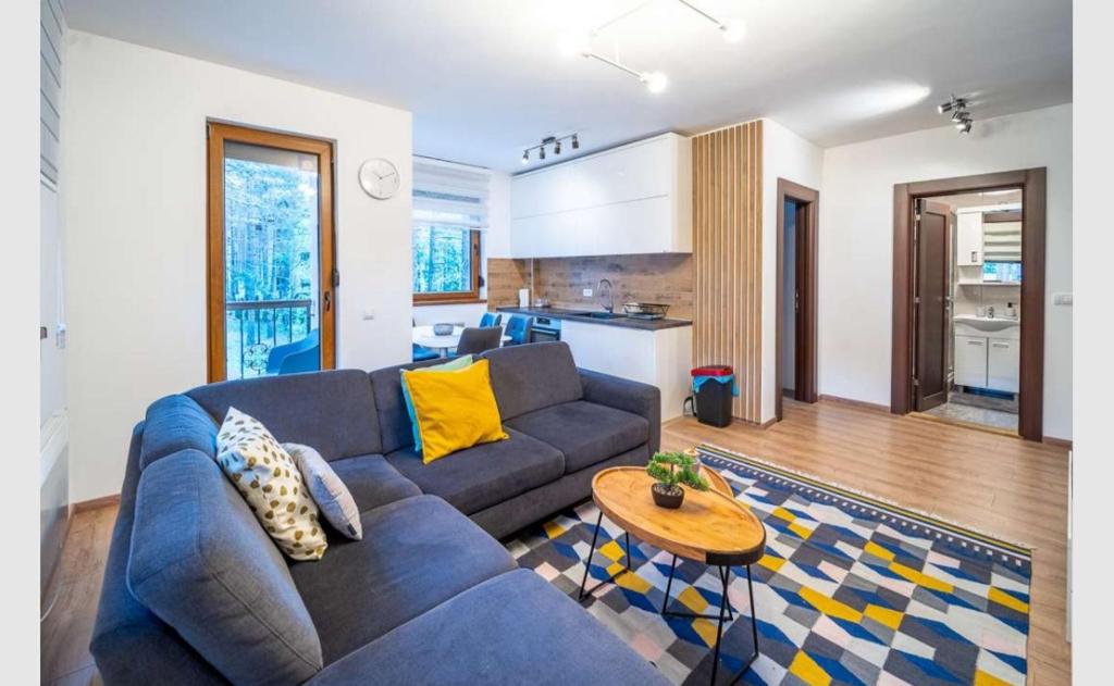 a living room with a blue couch and a kitchen at Apartman Pavle in Zlatibor
