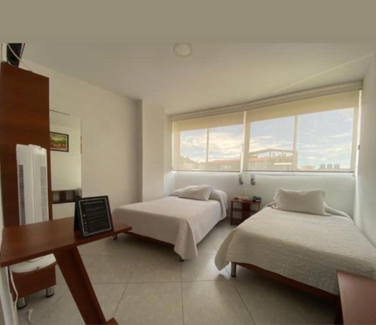 巴尔博萨Hotel Manhattan Barbosa的一间卧室，有两张床、一张书桌和一扇窗户
