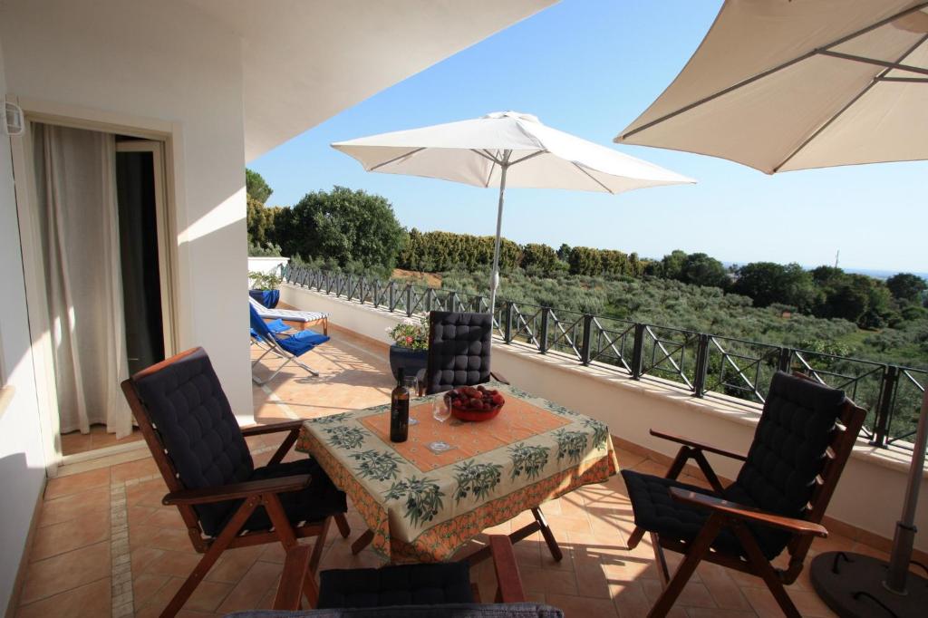 stół i krzesła z parasolem na balkonie w obiekcie Villa Stauder w mieście Genzano di Roma
