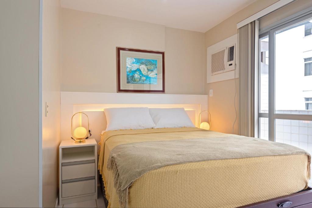 a bedroom with a bed with two lamps and a window at Studio com vista para o mar no centro de Guarapari com Wifi in Guarapari