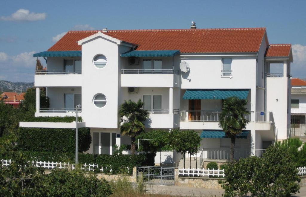 un immeuble blanc avec un toit rouge dans l'établissement Apartments Beti - 70 m from sea, à Betina