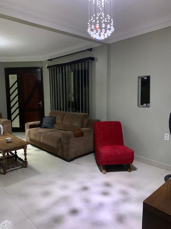 sala de estar con sofá y silla roja en Casa Oliveiras, en Itajaí