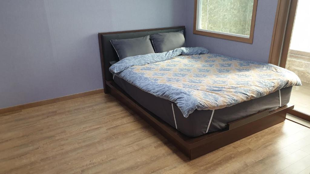 Ce lit se trouve dans une chambre dotée de parquet. dans l'établissement Geoje Seaside Luxury Family Villa, à Geoje