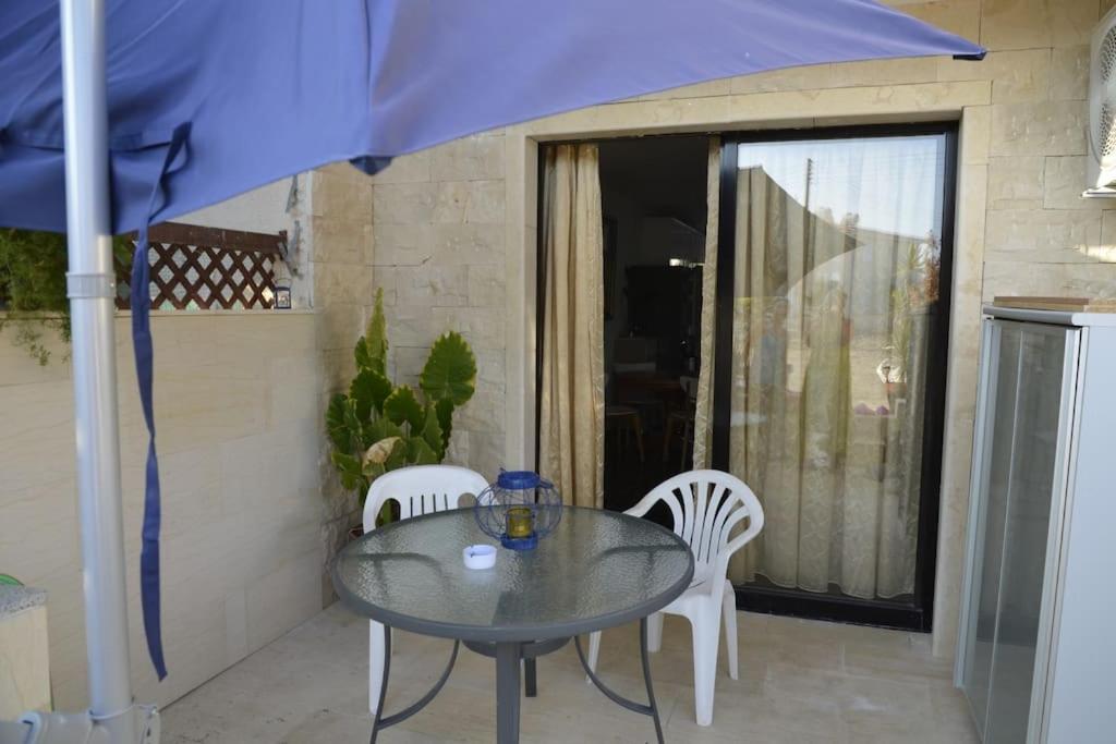 una mesa con 2 sillas y una sombrilla azul en Isabella court Townhouse near Venus beach and Lidl, en Pafos