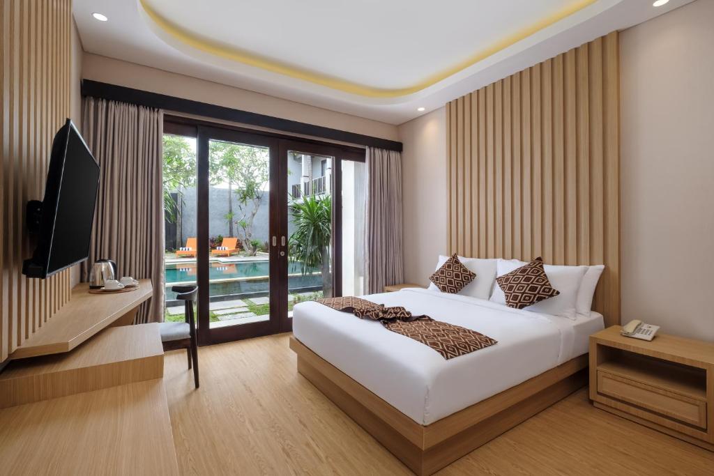 a bedroom with a bed and a television and a pool at ABISHA Hotel Sanur in Sanur