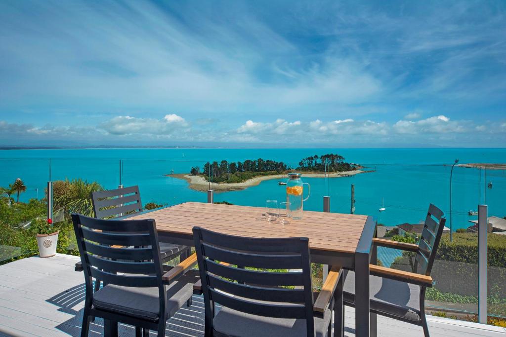 a wooden table with chairs and a view of the ocean at Ocean Vista in Nelson