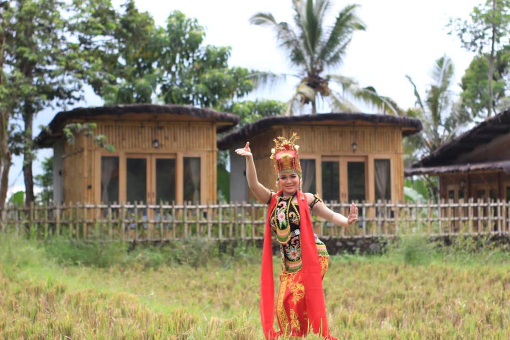a woman standing in a field in front of a building at Sawah Ijen in Licin