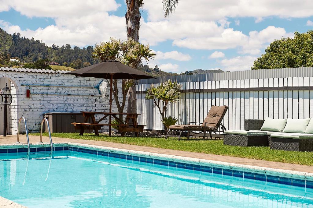 einen Pool mit Sonnenschirm, Tisch und Stühlen in der Unterkunft Rolleston Motel Thames - Wenzel Motels in Thames