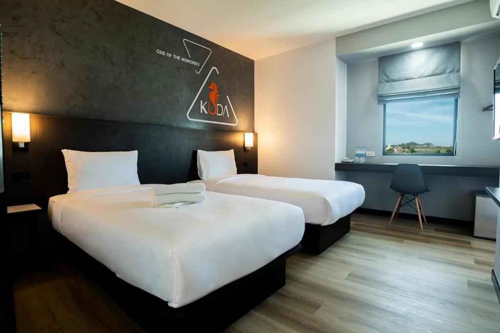 a hotel room with two beds and a window at Kuda Asia Hotel Bang Saen in Bangsaen