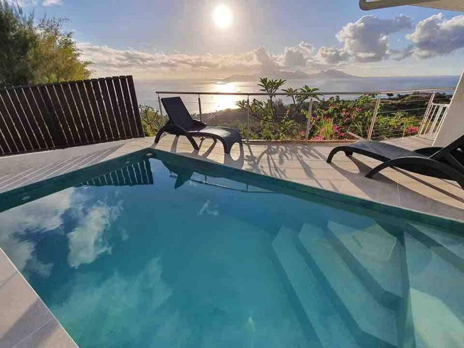 a swimming pool with chairs and a view of the ocean at Tahiti Moetama Cosy Lodge - VILLA ITI in Punaauia