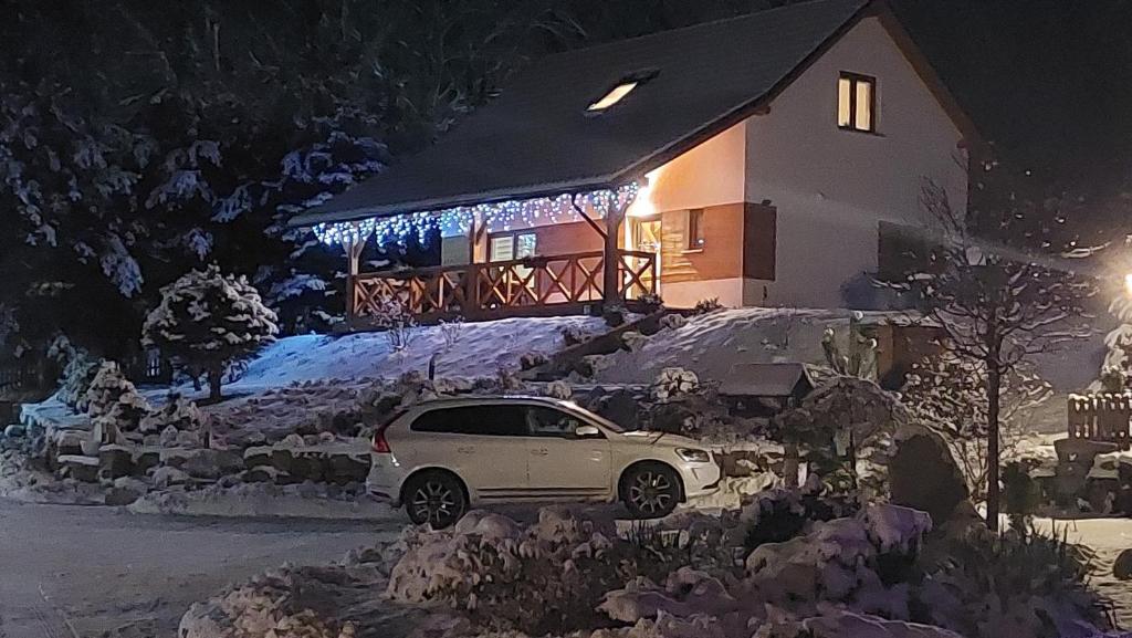 une voiture garée devant une maison aux lumières de Noël dans l'établissement Zielony Zakątek 2, à Sosnówka