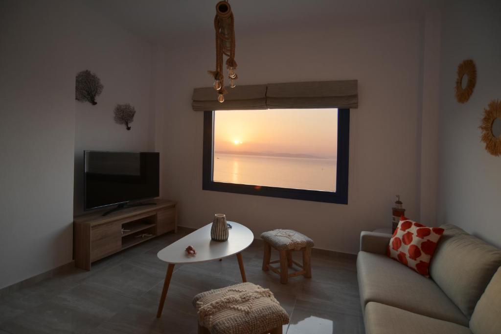 a living room with a couch and a tv and a table at Kea live in Blue Villa with Pool - Cyclades in Melissaki