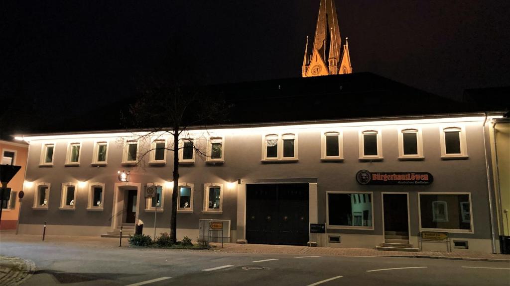 un edificio blanco con una torre de reloj en el fondo en BürgerhausLöwen, en Philippsburg