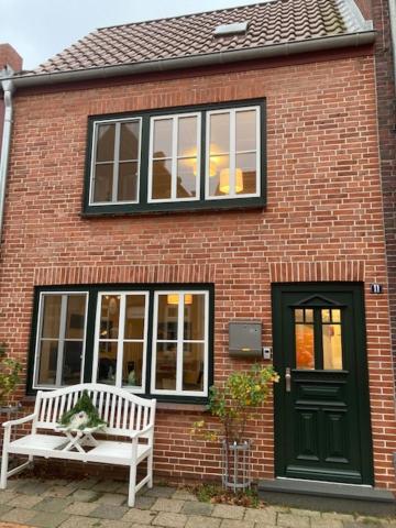 une maison en briques avec un banc blanc et une porte verte dans l'établissement P11 Vakantiehuis, à Friedrichstadt