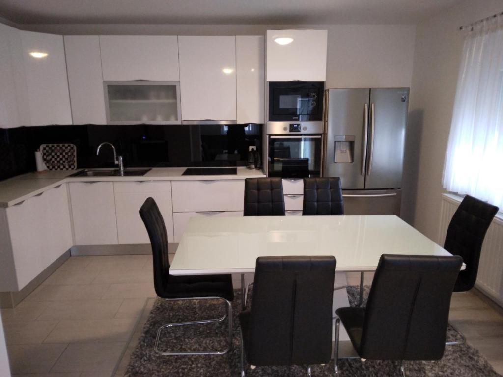 uma cozinha com uma mesa branca e cadeiras pretas em Apartmani Đerek em Posusje