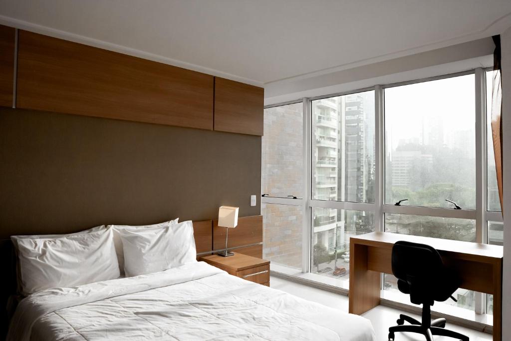 a bedroom with a bed and a desk and a window at Duplex Suite NYC Berrini 511 in Sao Paulo