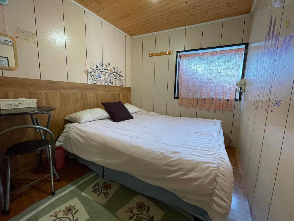 a small bedroom with a bed and a table at Linyuan Village in Jiufen