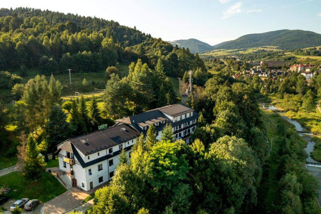 an aerial view of a building in a valley with a river at Dom Wczasowy SZCZYT in Muszyna