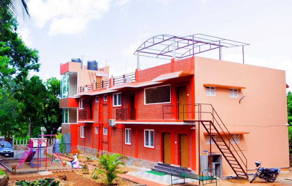 un edificio rojo con un parque infantil delante de él en Laughing Waters Fine Stay, en Kuttālam
