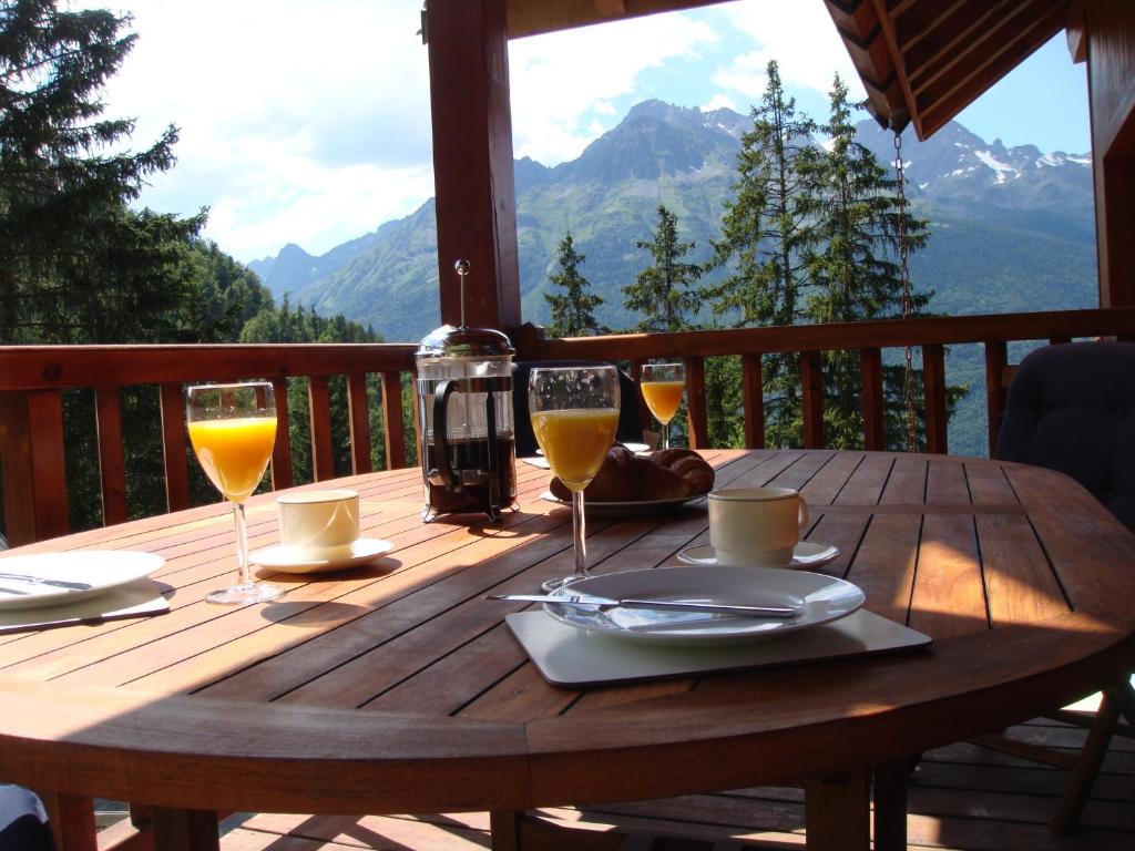 a wooden table with glasses of wine on a balcony at Chalet Clementine in Oz