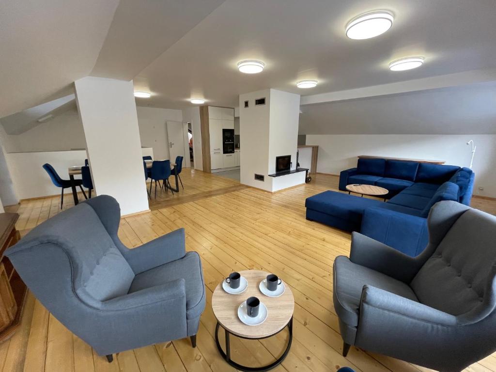Una sala de estar con sofás azules y una mesa. en Salmopolskie Zacisze, en Szczyrk