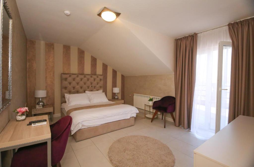um quarto com uma cama, uma secretária e uma janela em Bajadera Lux em Belgrado