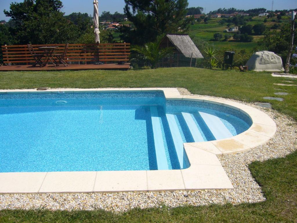 a swimming pool in a yard next to a field at Casa Vila Palmeira in Fermelã