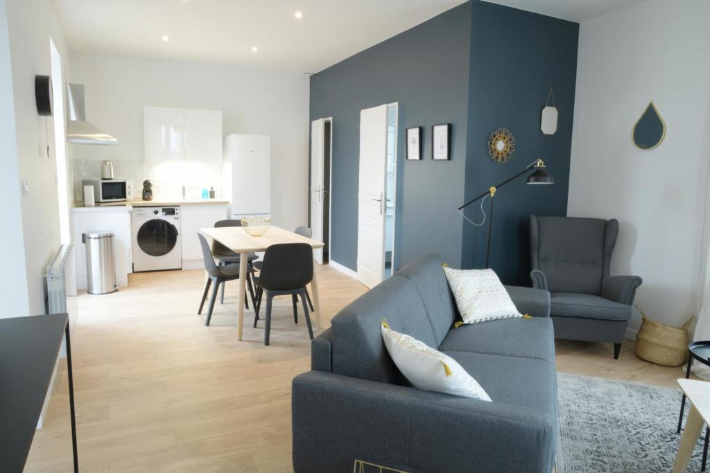 a living room with a blue couch and a table at T2 de 55m2 avec toit terrasse, hyper centre, wifi, draps, savons et serviettes fournis in Cognac