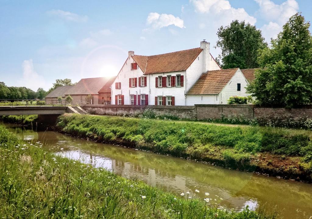 a white building next to a river with a bridge at B&B Hullebrug in Heist-op-den-Berg