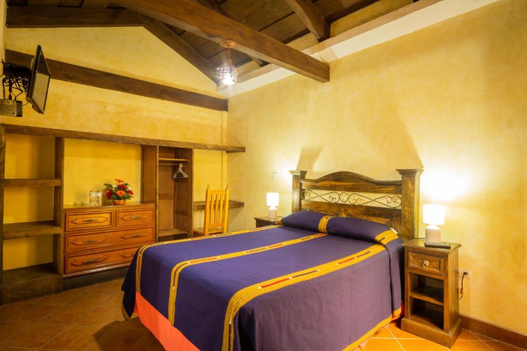 ein Schlafzimmer mit einem Bett und einer Kommode in einem Zimmer in der Unterkunft Hotel Maya Ik' in Antigua Guatemala