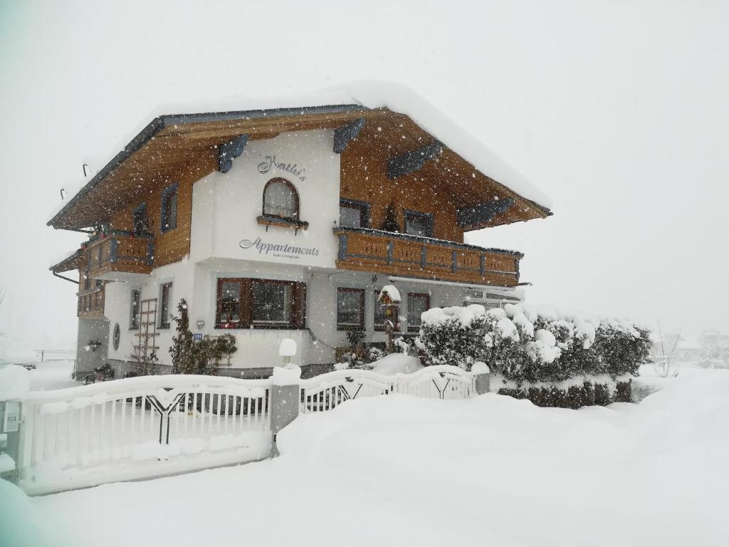 a snow covered house with a fence in front of it at Kathis Appartement in Flachau