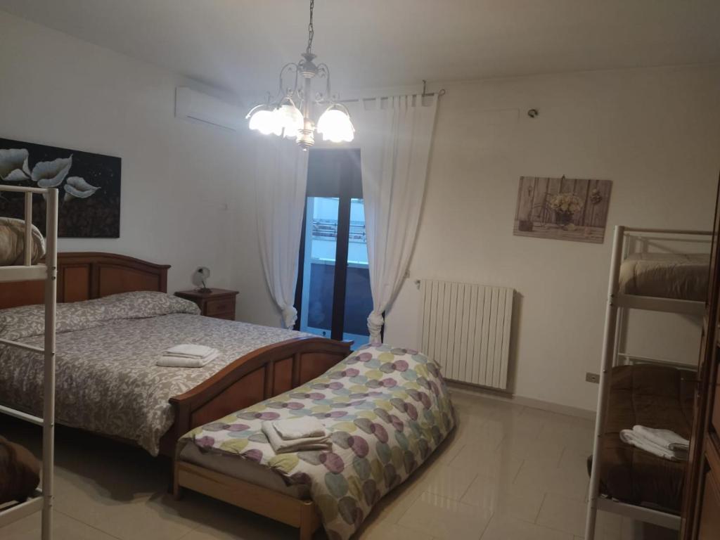 1 dormitorio con cama y lámpara de araña en "La casa di Mariagrazia" rooms con cucina condivisa e terrazza, en Sammichele di Bari