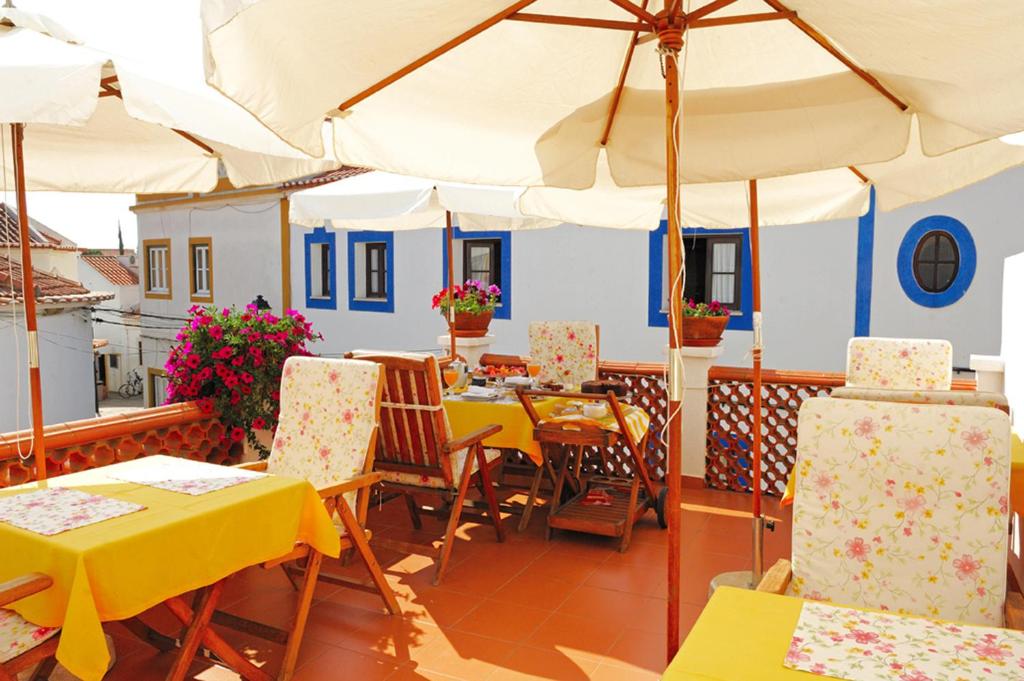 ein Restaurant mit Tischen, Stühlen und einem Sonnenschirm in der Unterkunft Casa Do Adro Da Igreja Turismo De Habitação in Vila Nova de Milfontes