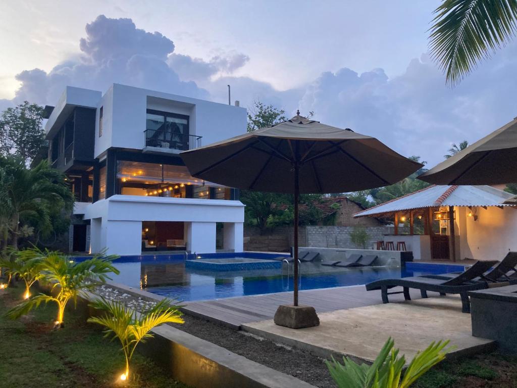 um guarda-chuva em frente a uma casa com piscina em Handagedara Resort & Spa em Mirissa