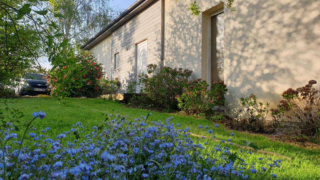 ein Haus mit blauen Blumen im Hof in der Unterkunft Grande maison avec SPA proche de CAEN et de la mer in Brouay