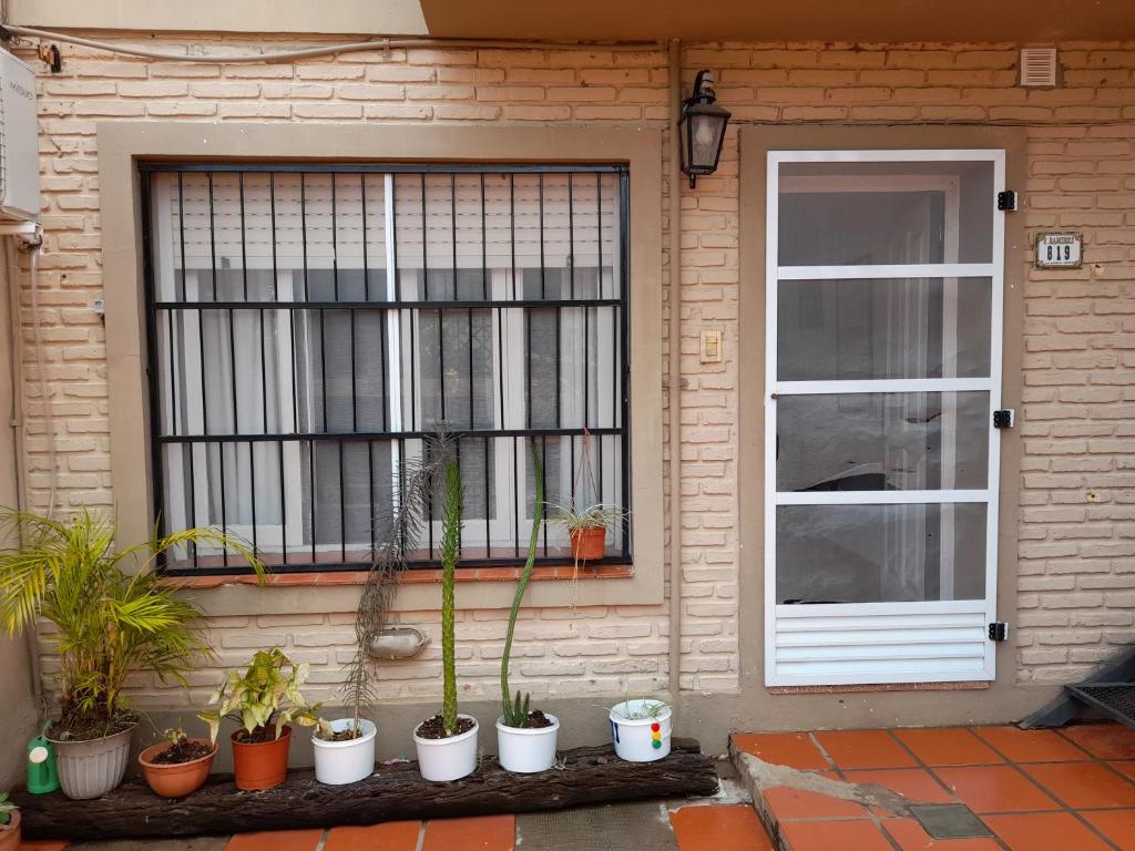 a house with a window and a bunch of potted plants at Casa cerca del microcentro y costanera in Posadas