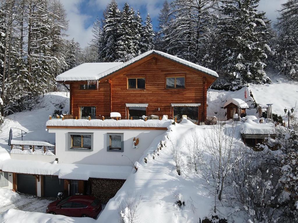 a house covered in snow with a car parked in front at Chalet Aigle in Crans-Montana