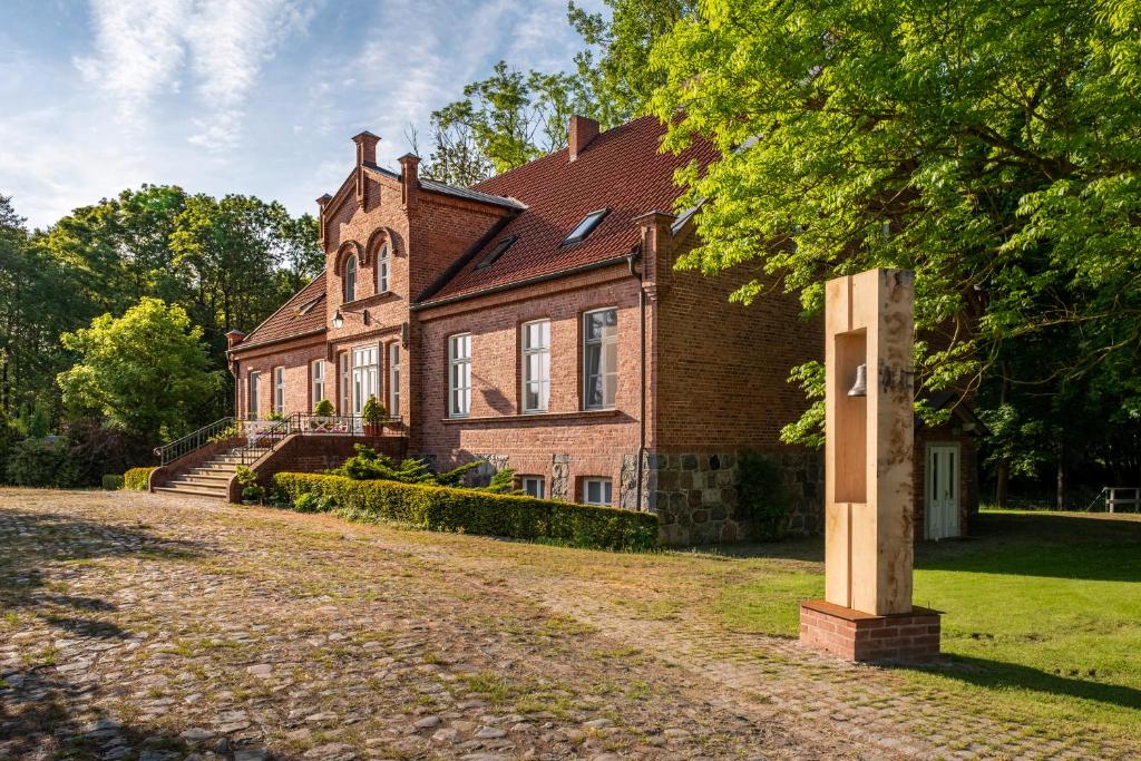 ein großes Backsteinhaus mit einem Baum davor in der Unterkunft Gutshof Falkenhagen in Falkenhagen