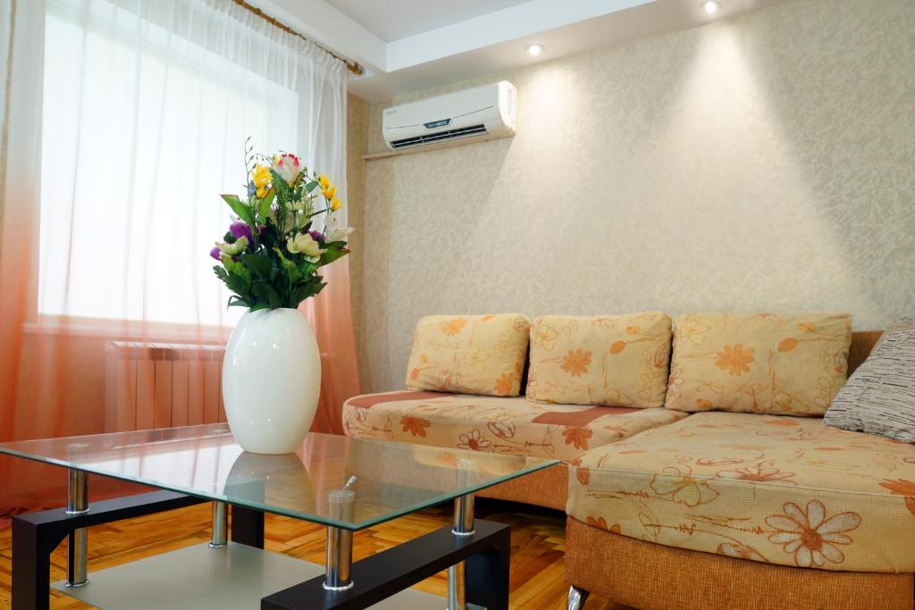 a living room with a couch and a vase with flowers at 2 Rooms Semi-luxury Apt on 39-H Nezalezhnoi Ukrаiny Street next to the city council (Walk of Fame) in Zaporozhye