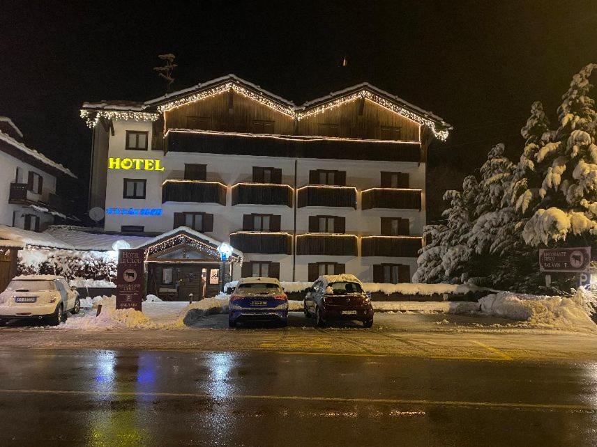 twee auto's geparkeerd voor een hotel 's nachts bij Hotel Le Clou in Arvier