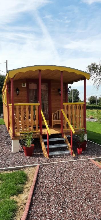 a tiny house with a porch and stairs in a yard at La Claud'Roulotte - Gîte du Moulin 62130 Pierremont in Pierremont