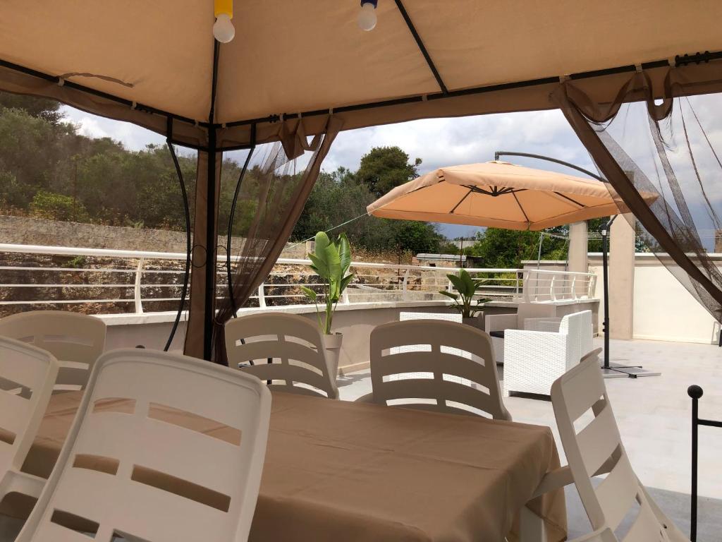 - une table, des chaises et un parasol sur la terrasse dans l'établissement Apulia Tourist Salento, à Gemini