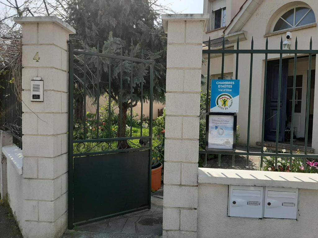 een groene poort voor een gebouw bij LE CLOS D'HERBLAY Chambres d'Hôtes in Herblay