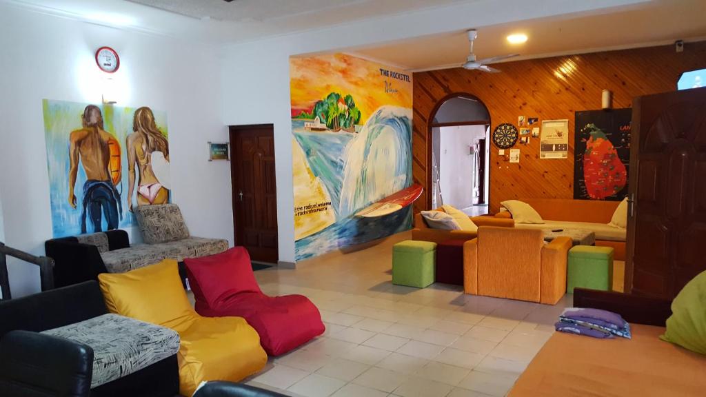 a living room with colorful furniture and paintings on the walls at The backpack hub at weligama in Weligama