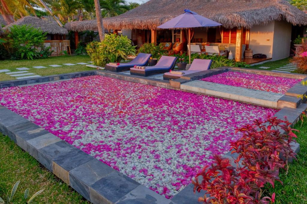 uma piscina coberta de flores cor-de-rosa em frente a uma casa em Luxury Sakina Villa - Beachfront em Dzamandzar