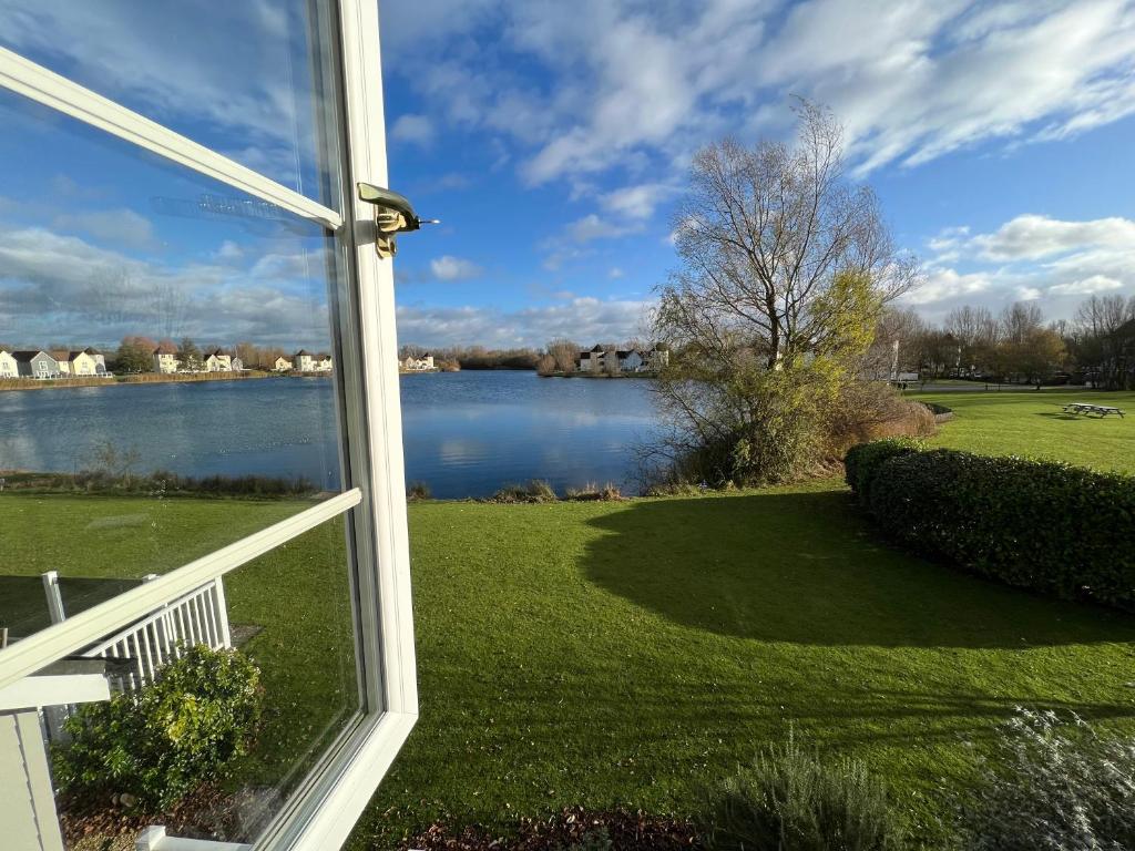 a window view of a lake from a house at Barnsley, Turret House Windrush Lake in South Cerney