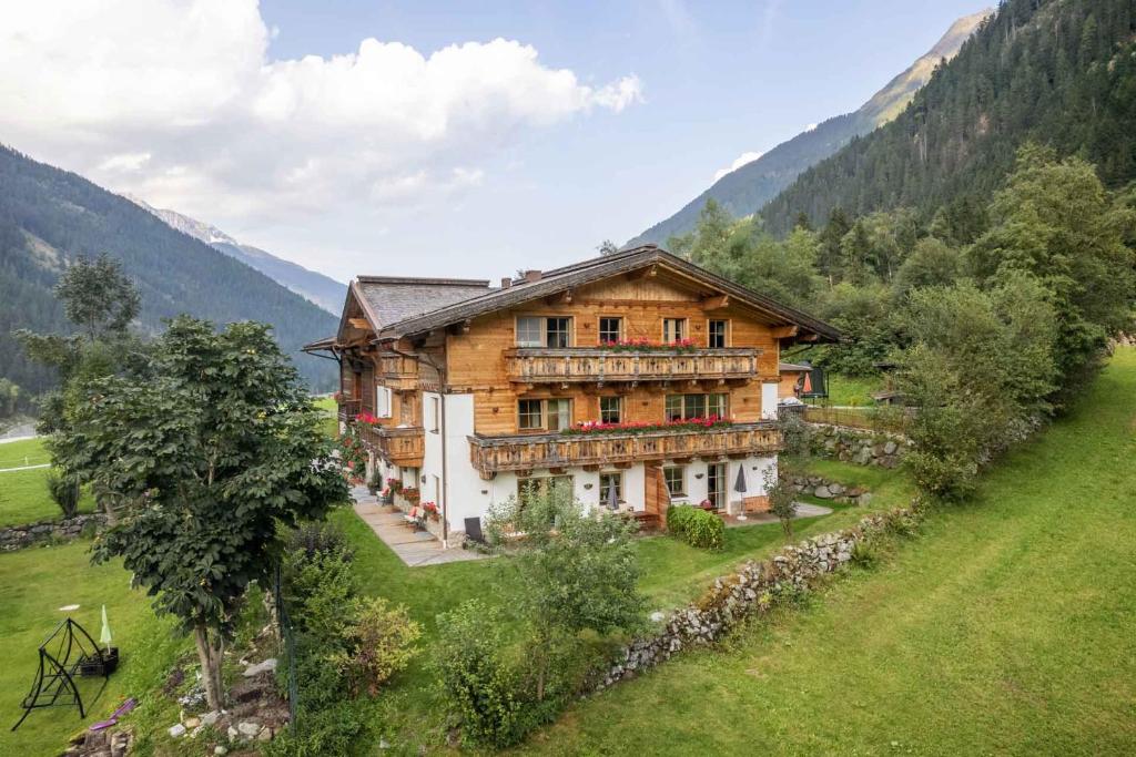 ein großes Holzhaus auf einem Hügel auf einem Feld in der Unterkunft Landhaus Wildes Wasser in Neustift im Stubaital