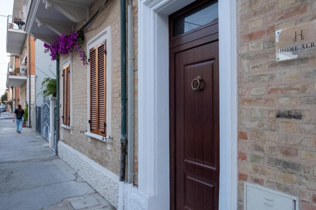 una porta marrone su un edificio di mattoni su una strada di Home Alba "Rooms" a Porto Recanati