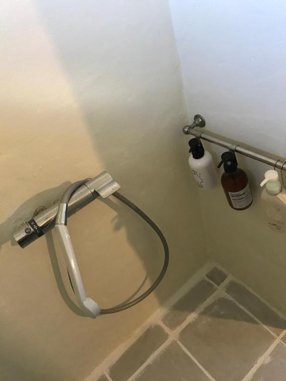 a shower nozzle in a bathroom with a toilet at Travelers House おーさんてぃん青空舎 in Taketomi