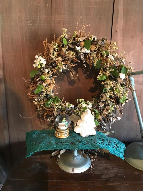a wreath on a wooden wall with a table at Travelers House おーさんてぃん青空舎 in Taketomi
